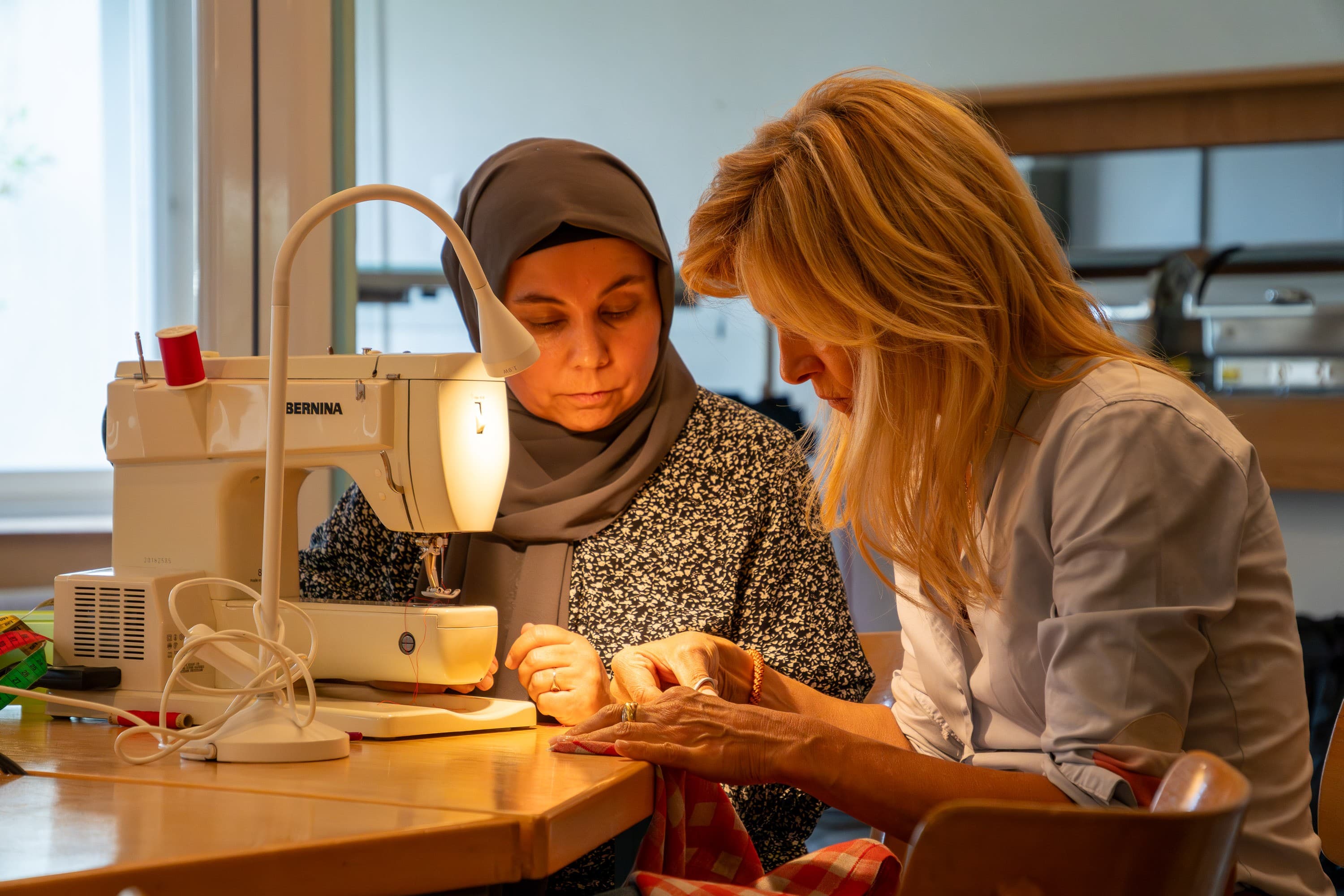 Dorothea Brinkmann zeigt Nasibe Muradi in der Flickstube einen Trick beim Nähen