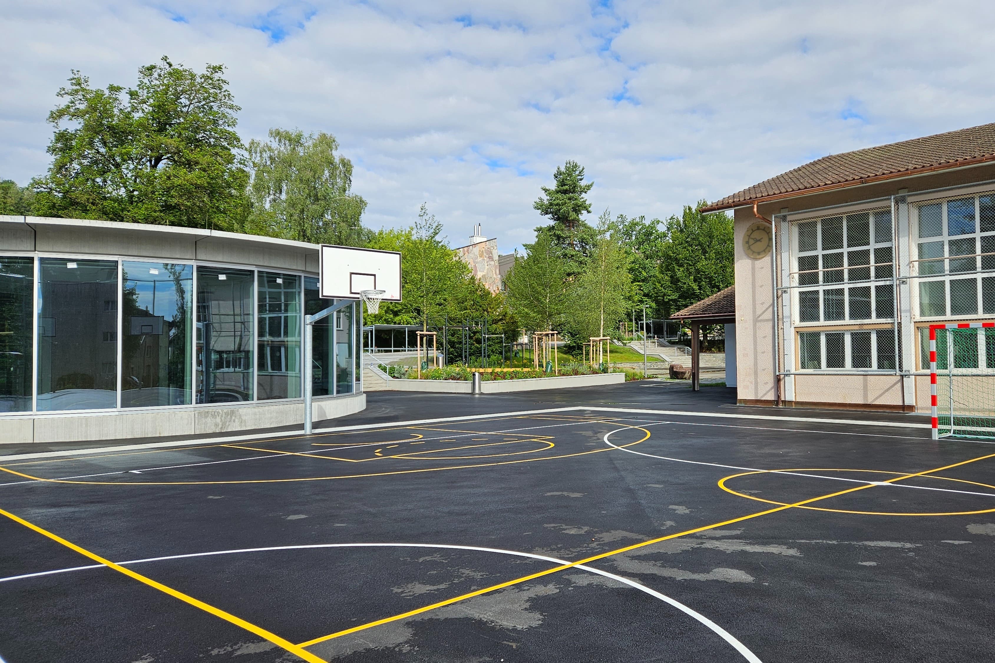 Die Doppelturnhalle liegt unter dem Hartplatz und ist über den runden Glasbau links im Bild zugänglich.
