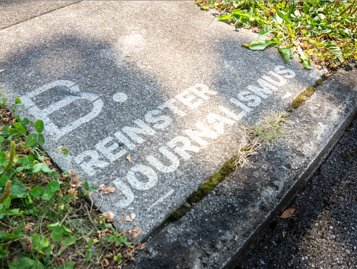 Reinster Journalismus mit Reverse-Graffiti auf einer Bodenplatte